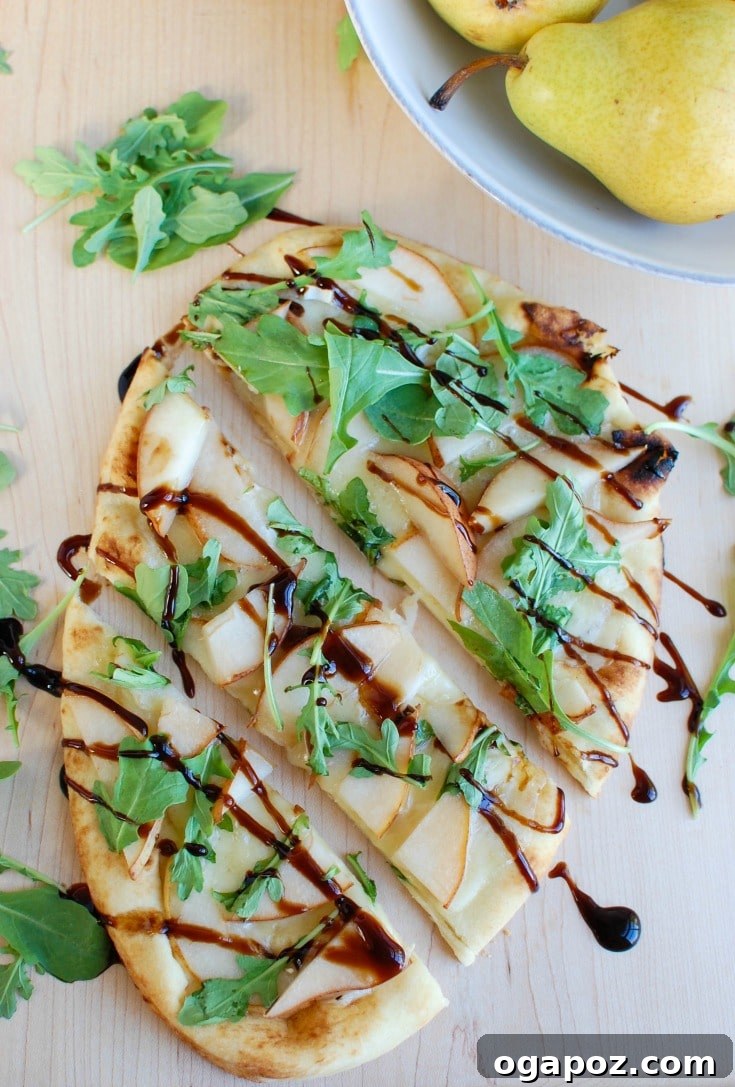 Gourmet Pear and Brie Flatbread 5 Warm Pear Brie Arugula Naan flatbread with a generous drizzle of balsamic glaze and fresh arugula, close up.