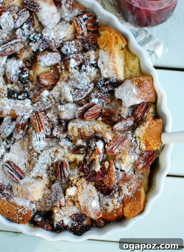 Make Ahead Eggnog French Toast Bake with Festive Cranberry Maple 4 Overnight Eggnog French Toast Bake with Cranberry Maple Syrup being prepared in a baking dish.
