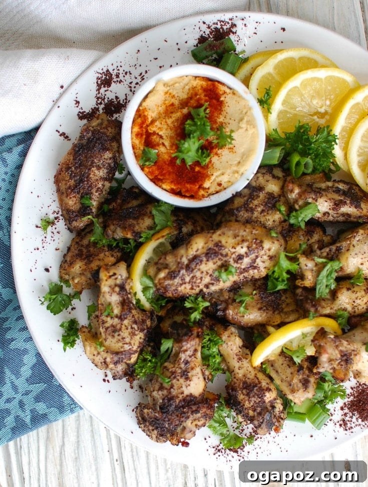 Zesty Sumac Lemon Wings 5 A large platter generously filled with golden, crispy Sumac Lemon Baked Chicken Wings, garnished with fresh herbs and lemon wedges, ready to be enjoyed.
