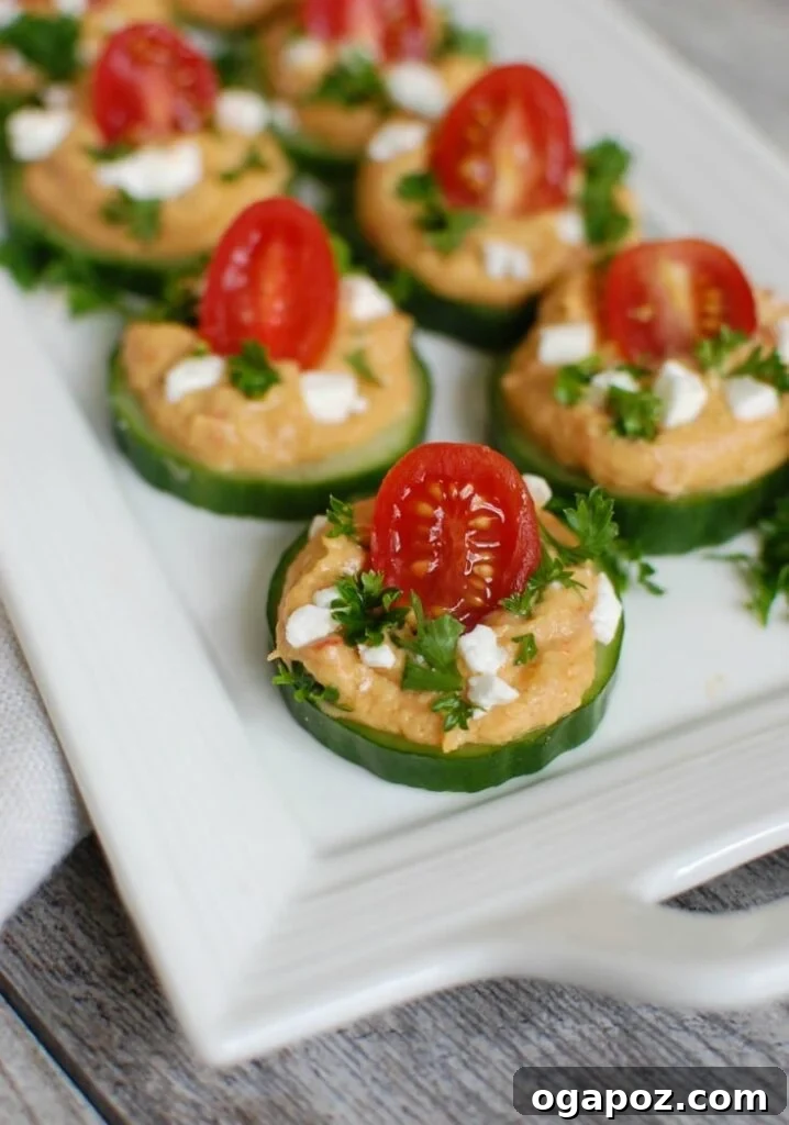 Cucumber Hummus Bites, perfect finger food and appetizer with roasted red pepper hummus, tomatoes, and feta cheese.