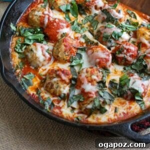 Delicious Skillet Tomato Basil Meatballs with melted cheese and fresh basil garnish
