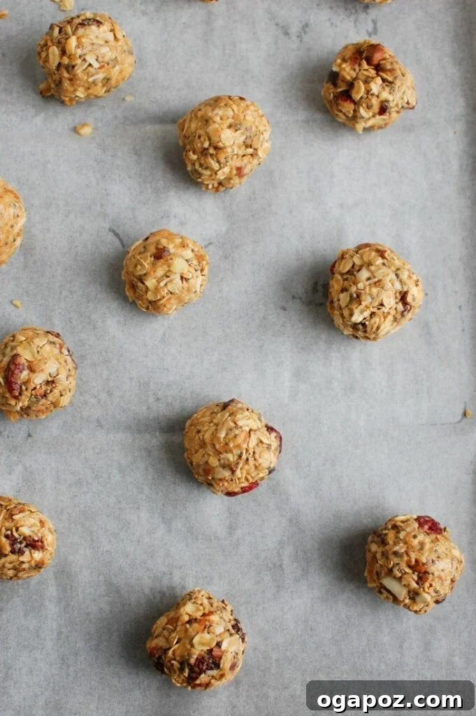Almond Cranberry Energy Balls 5 Rolled Cranberry Almond Energy Bites arranged neatly on wax paper on a baking sheet, ready for refrigeration.