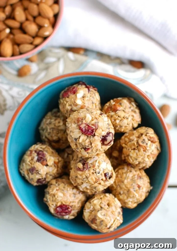 Almond Cranberry Energy Balls 6 A stack of Cranberry Almond Energy Bites with a bite taken out, showing the rich texture inside, on a wooden board.