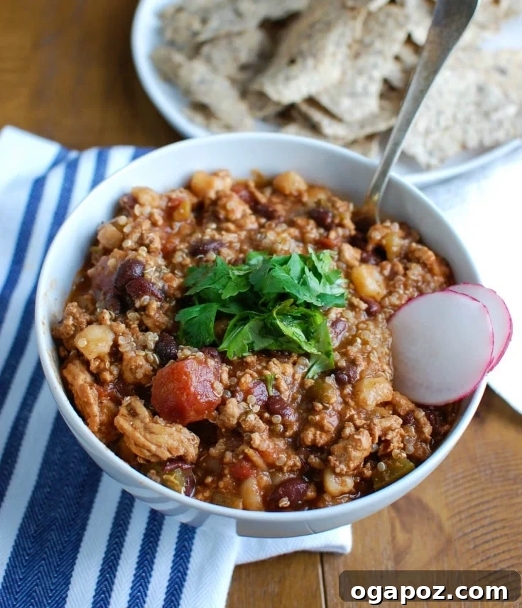 Hearty Slow Cooker Turkey Quinoa Chili 2 A steaming bowl of Slow Cooker Turkey Quinoa Chili garnished with fresh cilantro and sour cream.