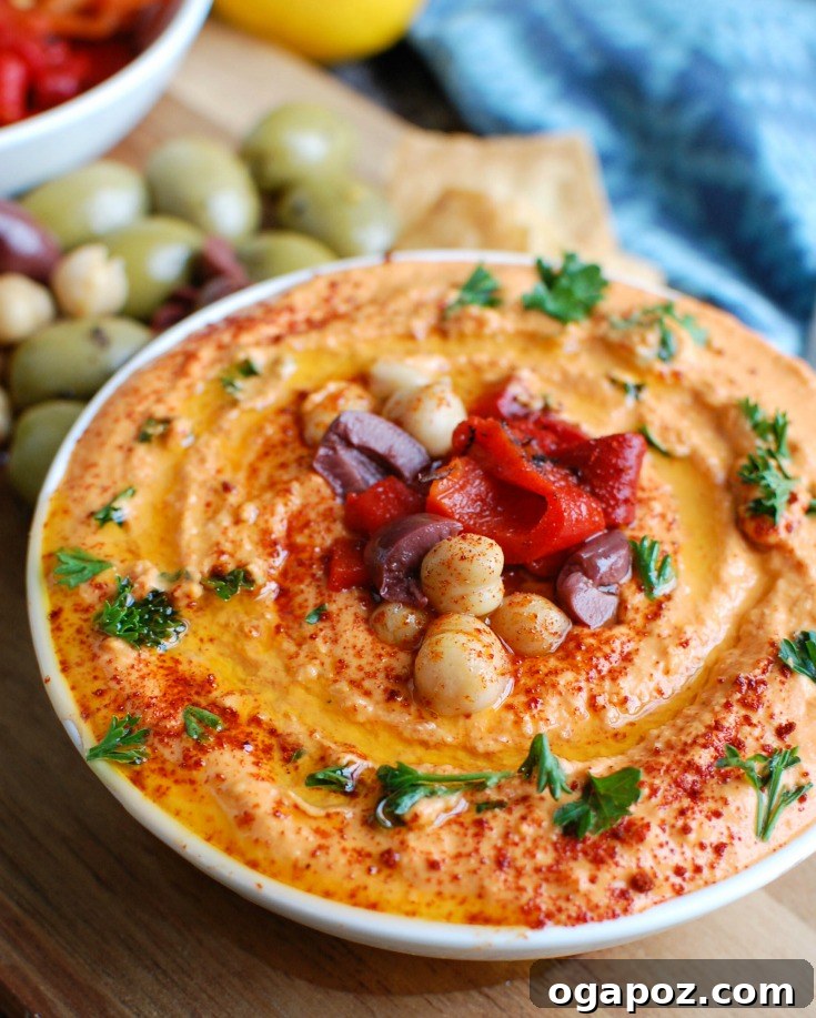 Creamy Roasted Red Pepper Greek Yogurt Hummus 2 Creamy Roasted Red Pepper Greek Yogurt Hummus served in a bowl with pita bread and fresh vegetables, showcasing its vibrant color and smooth texture.