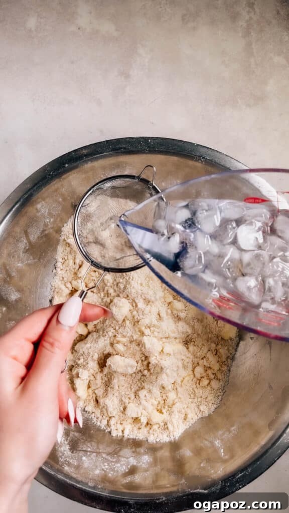 Foolproof Pie Crust You Can Make By Hand 9 Carefully pouring ice water through a sieve into the flour mixture.