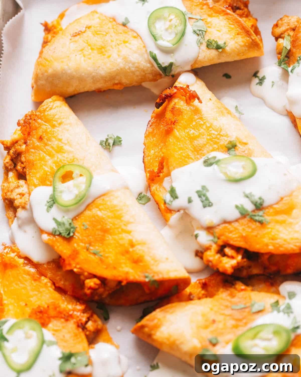 Golden Crispy Baked Chicken Tacos 7 Crispy baked chicken tacos on a baking sheet, topped with lime crema, jalapeno, and cilantro.