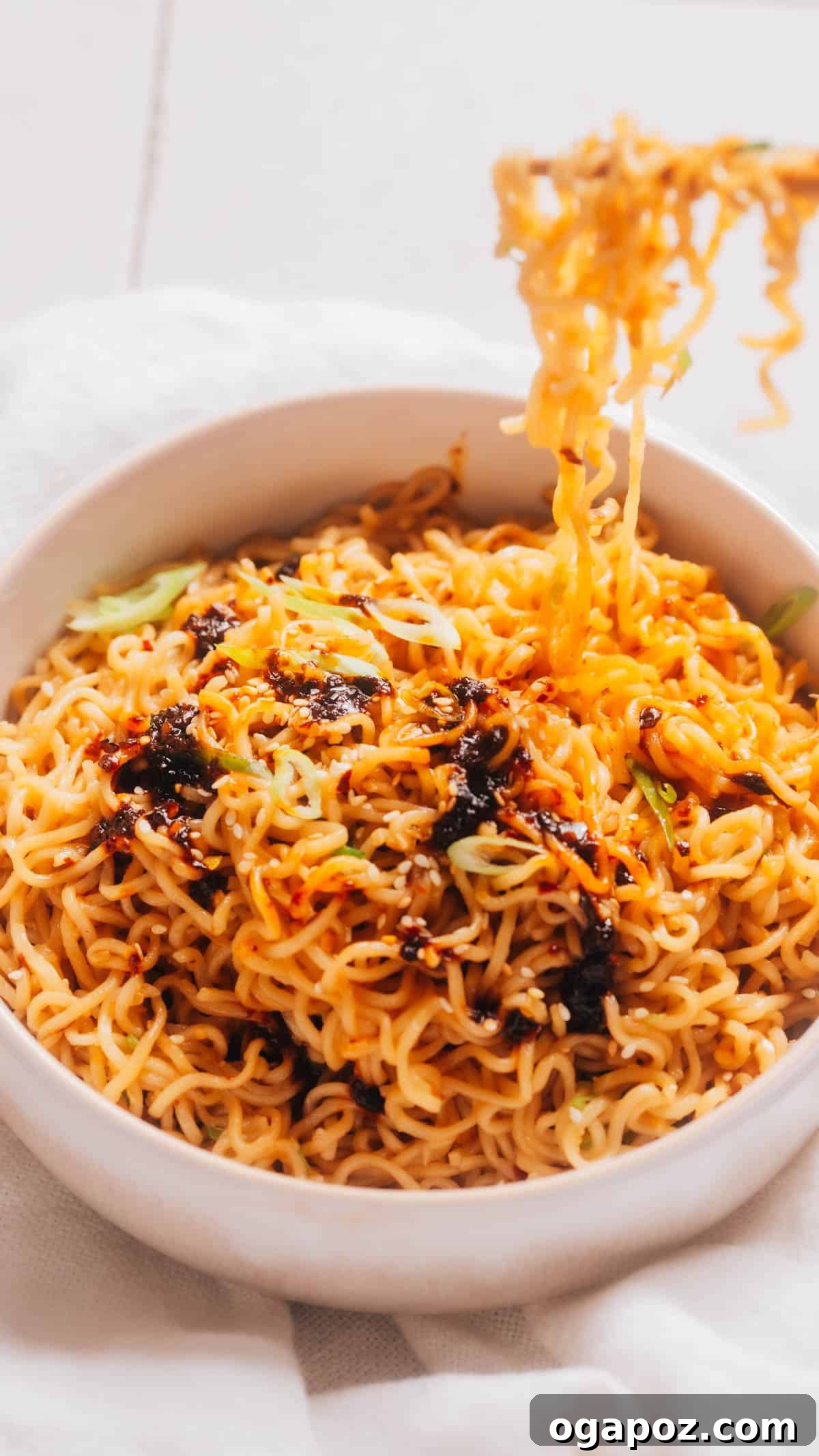 Fiery Chili Ramen 2 A vibrant bowl of Chili Oil Ramen, garnished generously with fresh green scallions and a tempting drizzle of red chili oil, highlighting its rich flavors.