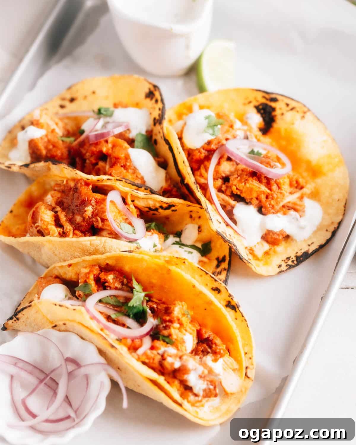 Vibrant Cilantro-Lime Drizzle 5 Pulled Pork Tacos generously drizzled with cilantro lime crema and garnished with thinly sliced red onions.