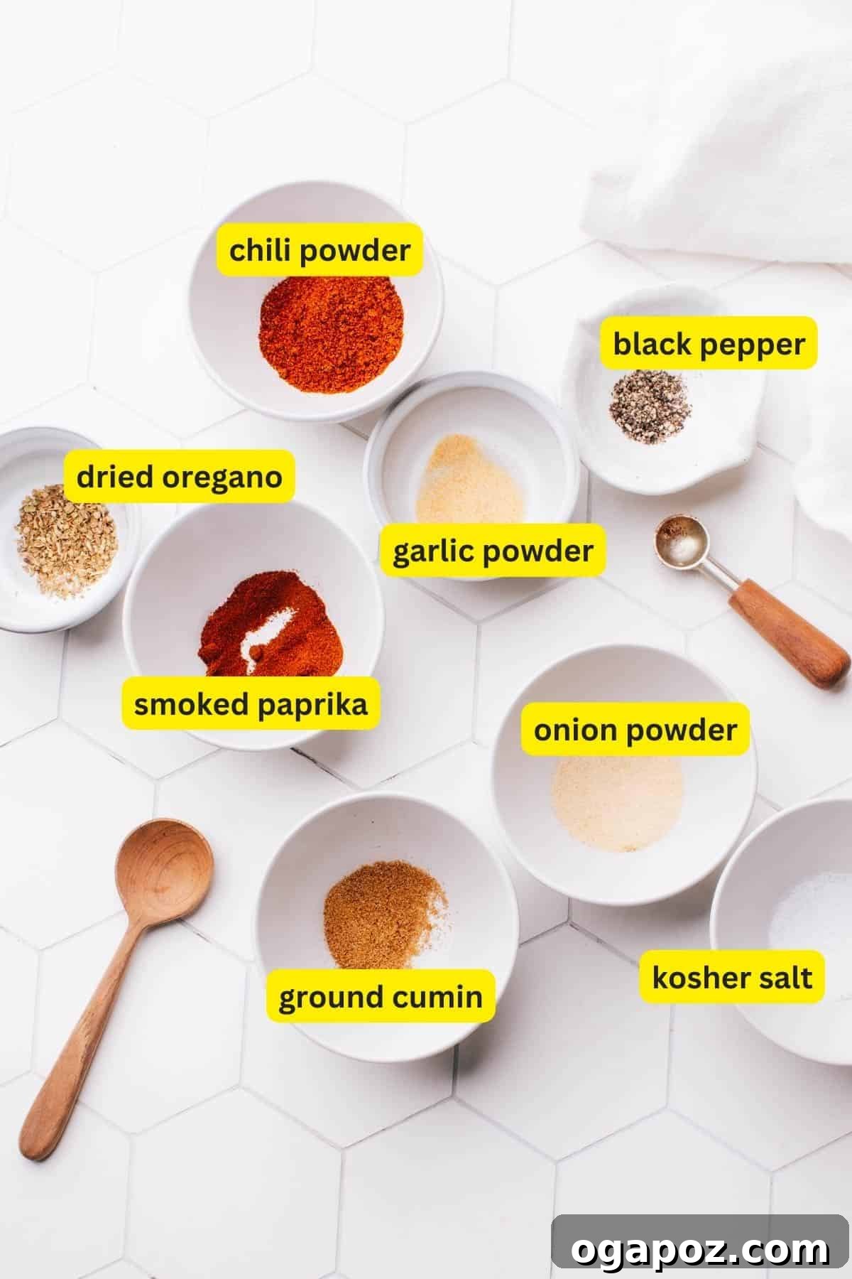 All the essential ingredients for homemade chicken taco seasoning neatly arranged on a kitchen countertop, featuring chili powder, ground cumin, onion powder, smoked paprika, garlic powder, dried oregano, kosher salt, and black pepper.