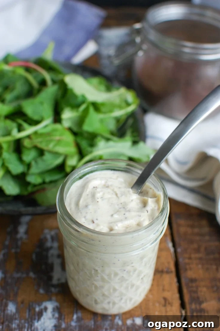 Creamy Tahini Yogurt Dressing 3 Tahini Yogurt Dressing being scooped with a spoon from a jar, highlighting its creamy texture