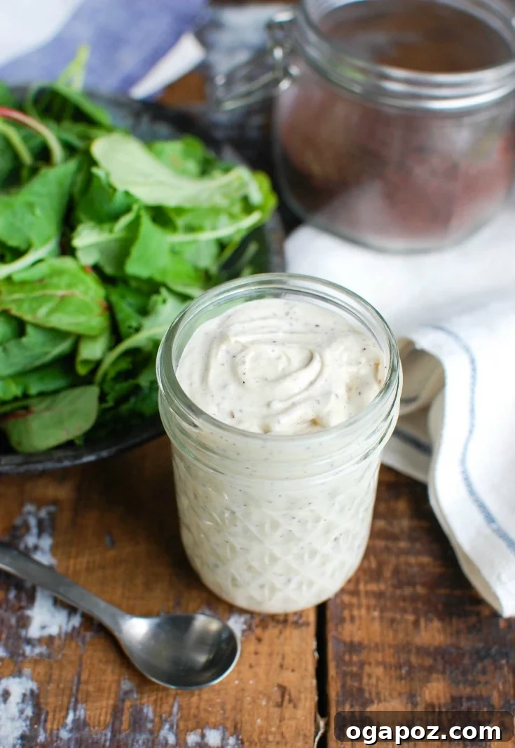 Creamy Tahini Yogurt Dressing 4 Tahini Yogurt Dressing in a jar, with a white napkin and a bowl of fresh ingredients in the background
