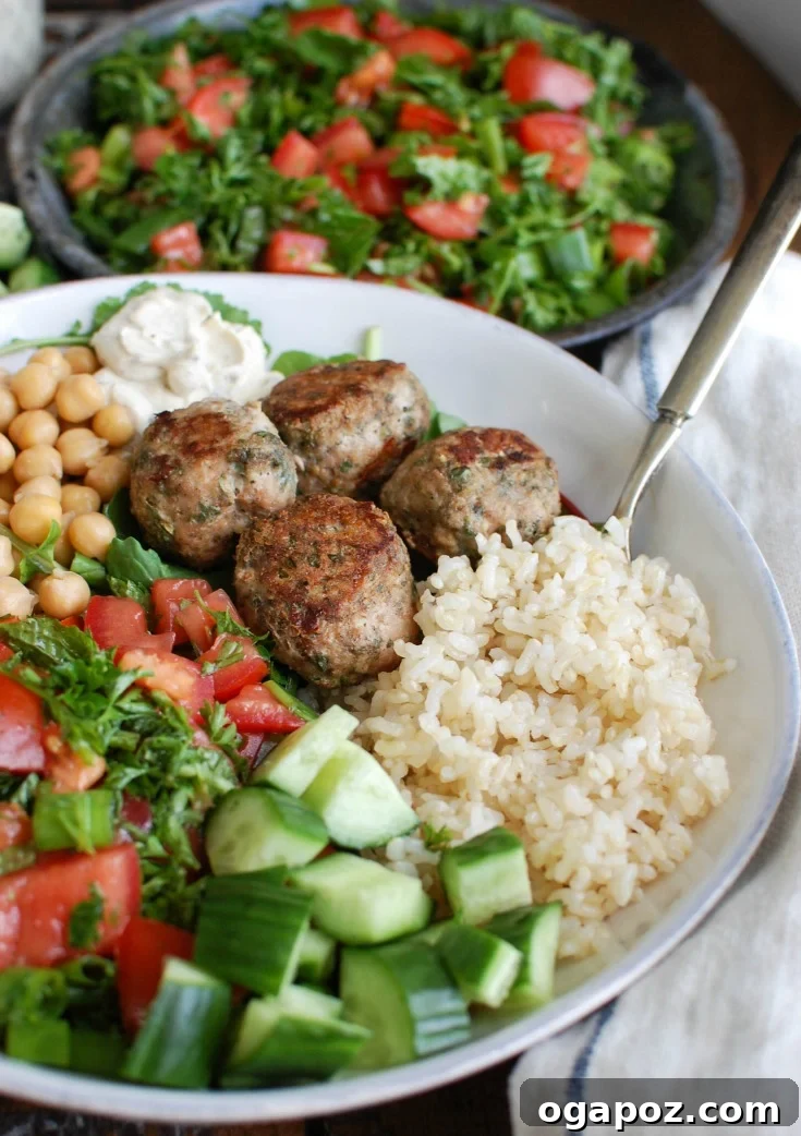Mediterranean Baked Turkey Meatballs in a bowl, garnished with fresh herbs and a drizzle of sauce.