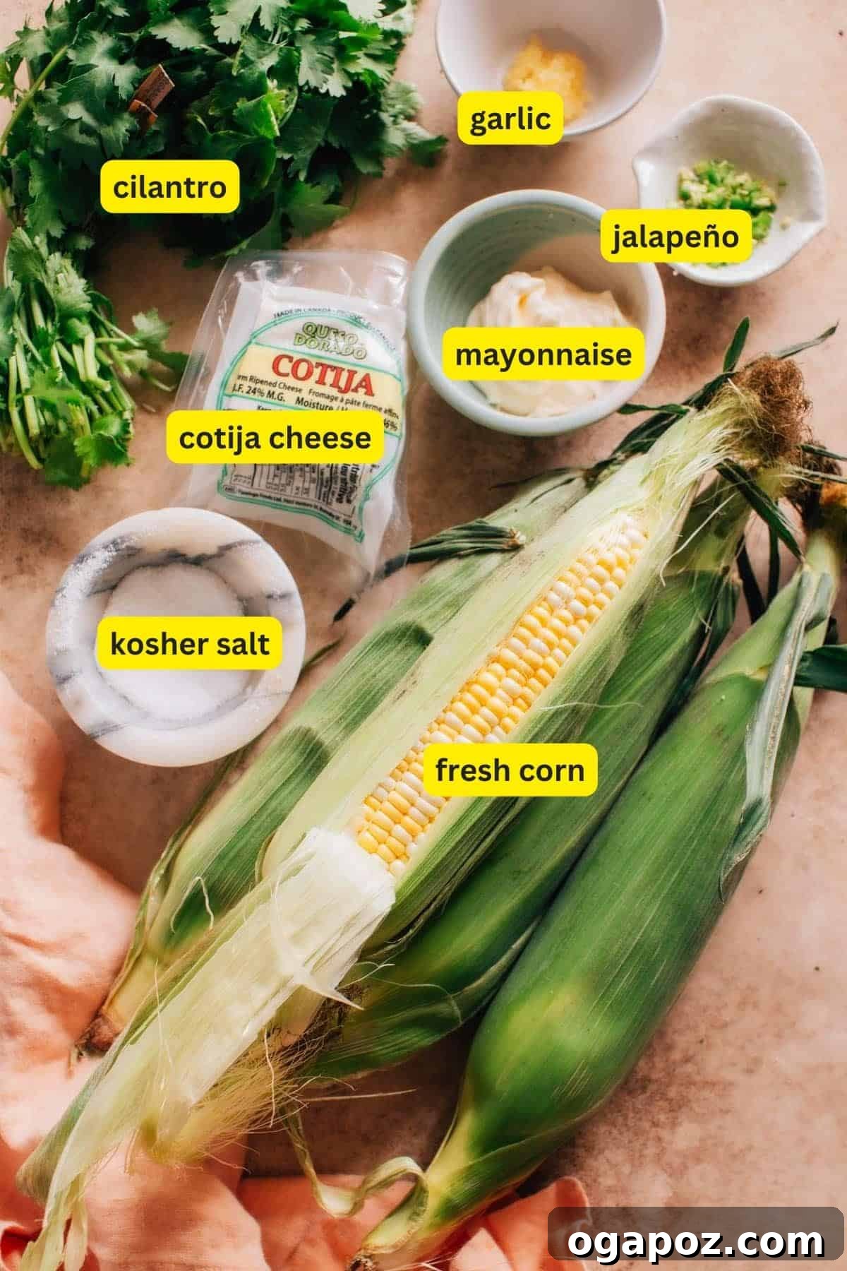 Fresh ingredients laid out for a Mexican Street Corn Salad recipe, including corn, limes, cilantro, mayonnaise, and cotija cheese.