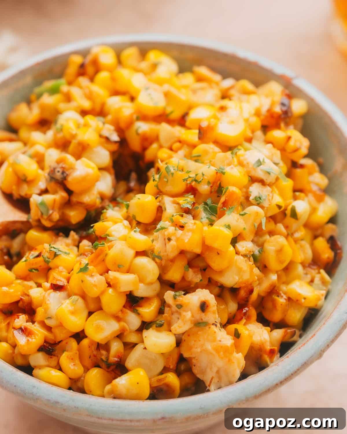 A beautifully presented bowl of Mexican Street Corn Salad (Esquites) with fresh cilantro and lime wedges.
