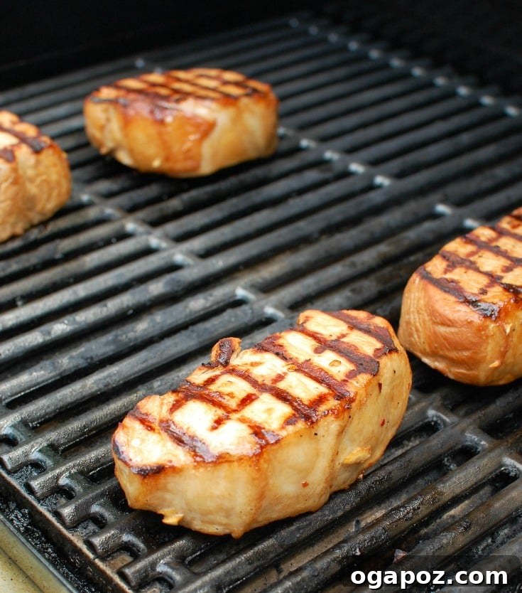 Sweet and Tangy Island Pork Chops 4 Close-up of Hawaiian pork chops sizzling on a hot grill, showing perfect grill marks and juicy texture as they cook outdoors.