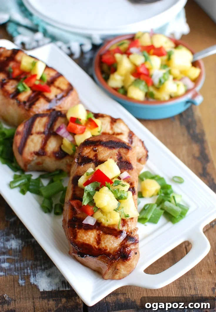 Sweet and Tangy Island Pork Chops 5 Grilled Hawaiian pork chop sliced and served with a vibrant pineapple salsa on top, on a white plate ready for a family dinner.
