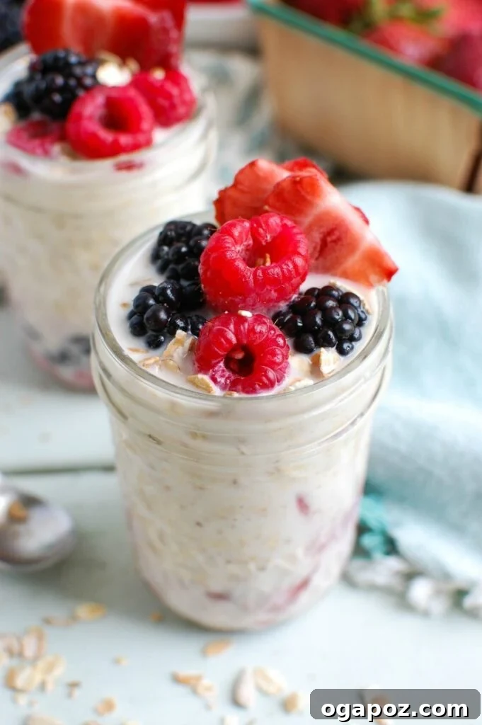 Triple Berry Bliss Overnight Oats 2 A beautifully presented jar of Overnight Triple Berry Oatmeal, showing layers of oats, Greek yogurt, milk, and vibrant blueberries, raspberries, and sliced strawberries, topped with fresh berries and chia seeds. Perfect for a healthy, quick breakfast or snack.
