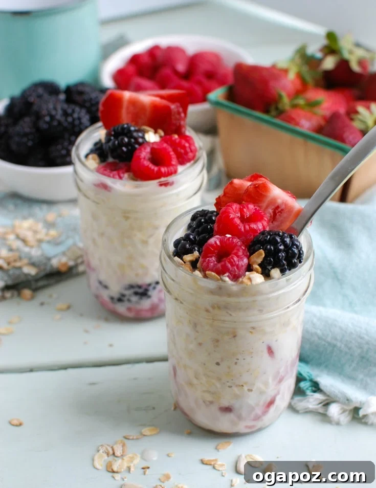 Triple Berry Bliss Overnight Oats 3 A collection of fresh ingredients laid out, including rolled oats, a bowl of mixed blueberries, raspberries, and strawberries, a bottle of milk, a container of Greek yogurt, and a small bottle of vanilla extract, all ready to be combined for Overnight Triple Berry Oatmeal.