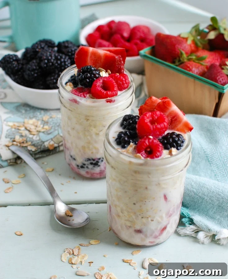 Triple Berry Bliss Overnight Oats 5 A person holding a mason jar filled with freshly prepared Overnight Triple Berry Oatmeal, garnished with additional berries and a sprinkle of chia seeds, against a softly blurred background. It conveys a sense of healthy eating and morning convenience.