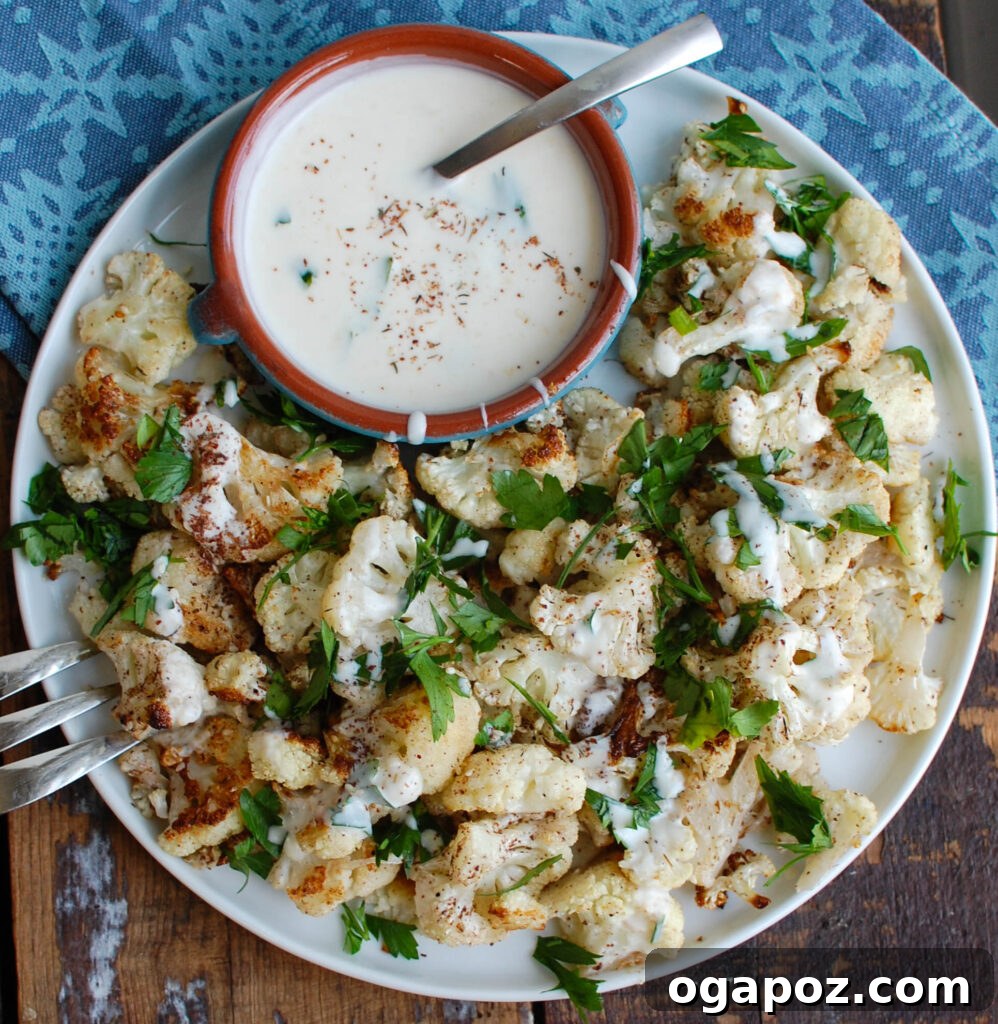 Za'atar Roasted Cauliflower with Creamy Tahini-Yogurt 7 A serving of Za'atar Roasted Cauliflower with Yogurt Tahini Sauce, garnished with fresh herbs.
