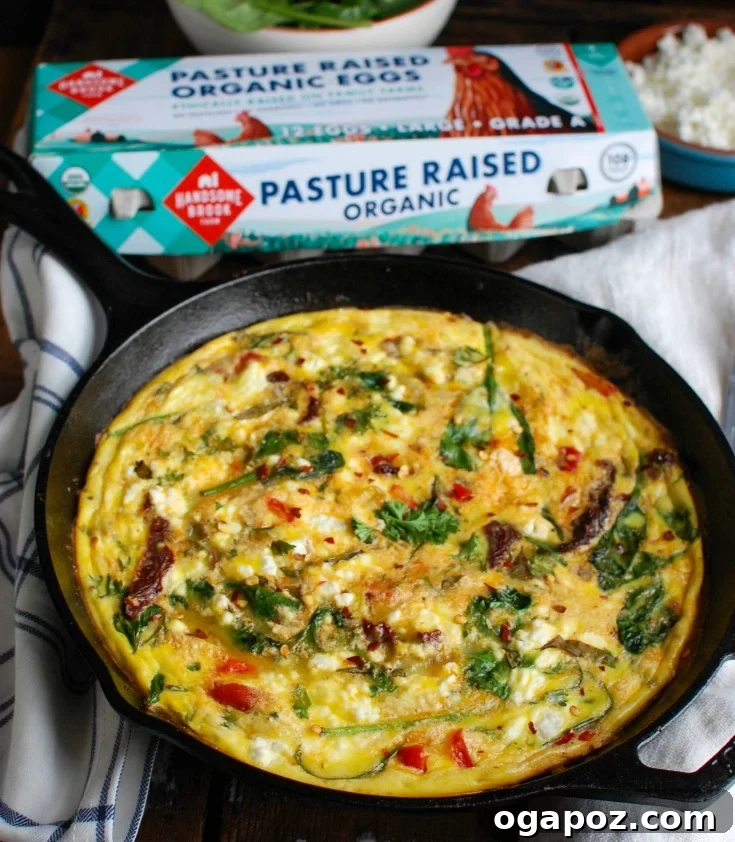 Sun-Kissed Tomato and Tangy Goat Cheese Frittata 2 A beautifully cooked Sun-Dried Tomato Goat Cheese Frittata, garnished with fresh herbs, ready to be served. It features visible chunks of sun-dried tomatoes, green spinach, and melted goat cheese.