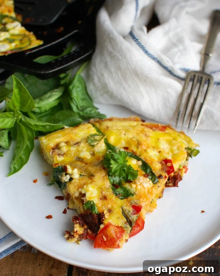 Sun-Kissed Tomato and Tangy Goat Cheese Frittata 3 A close-up shot of the Sun-Dried Tomato Goat Cheese Frittata baking in a cast iron skillet, showcasing the golden-brown edges and bubbling cheese.