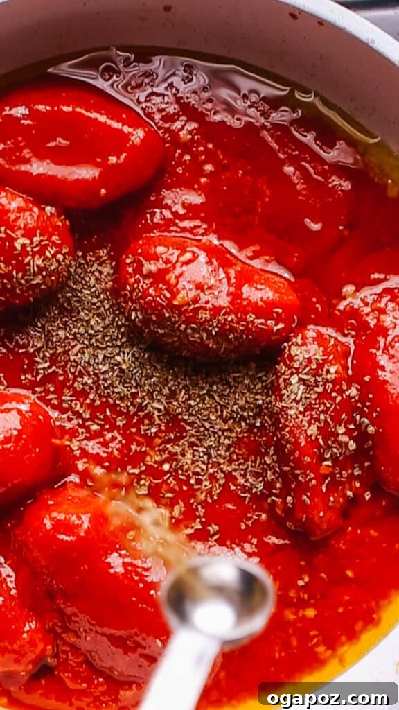The Best Homemade Pizza Sauce You'll Ever Make 10 A hand sprinkling dried herbs and red pepper flakes into simmering pizza sauce in a pan.