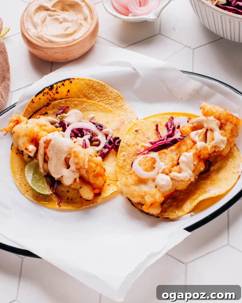 Instant 5-Minute Pickled Onions 7 Two delicious Baja fish tacos artfully presented on parchment paper, drizzled with flavorful Baja sauce and accompanied by a bed of crispy cabbage slaw and vibrant pickled onions.