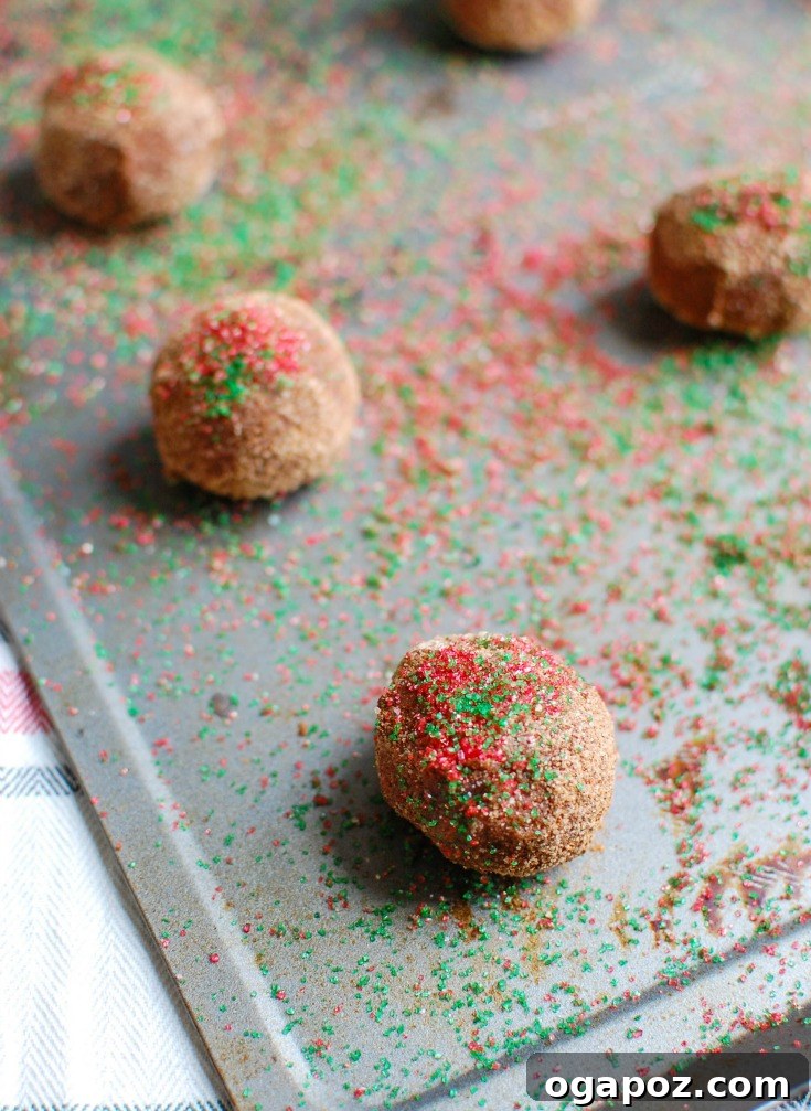 Irresistible Gluten-Free Chocolate Snickerdoodles 6 Gluten-Free Chocolate Snickerdoodle dough balls coated in sugar and sprinkles on a baking sheet