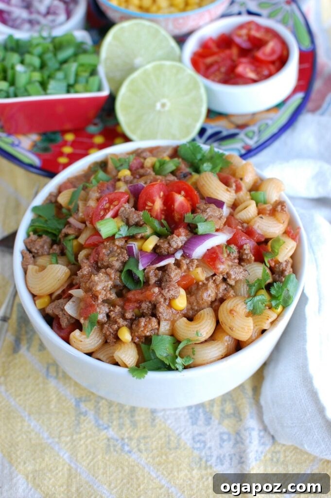 Easy One-Pan Taco Beef Pasta 2 A serving of One Skillet Beef Taco Pasta in a bowl, topped with fresh cilantro and sour cream