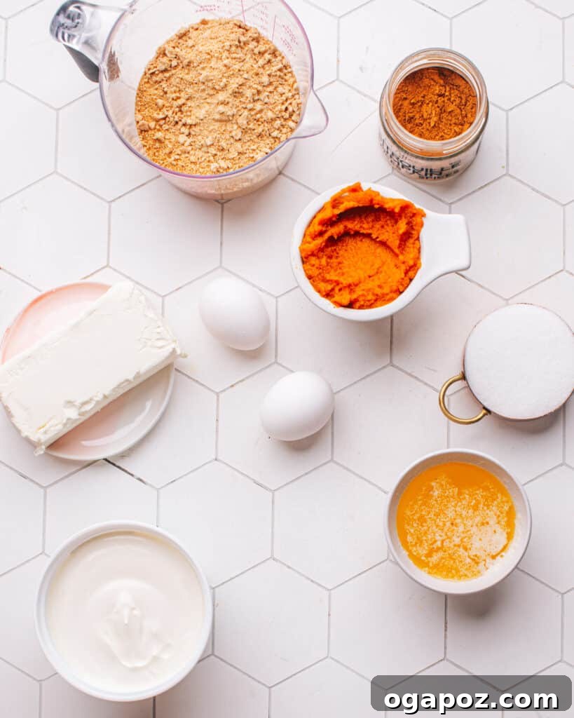A selection of fresh ingredients laid out on a table, including canned pumpkin puree, cream cheese, sour cream, sugar, eggs, vanilla extract, and graham cracker crumbs, ready for making Pumpkin Cheesecake Bars.