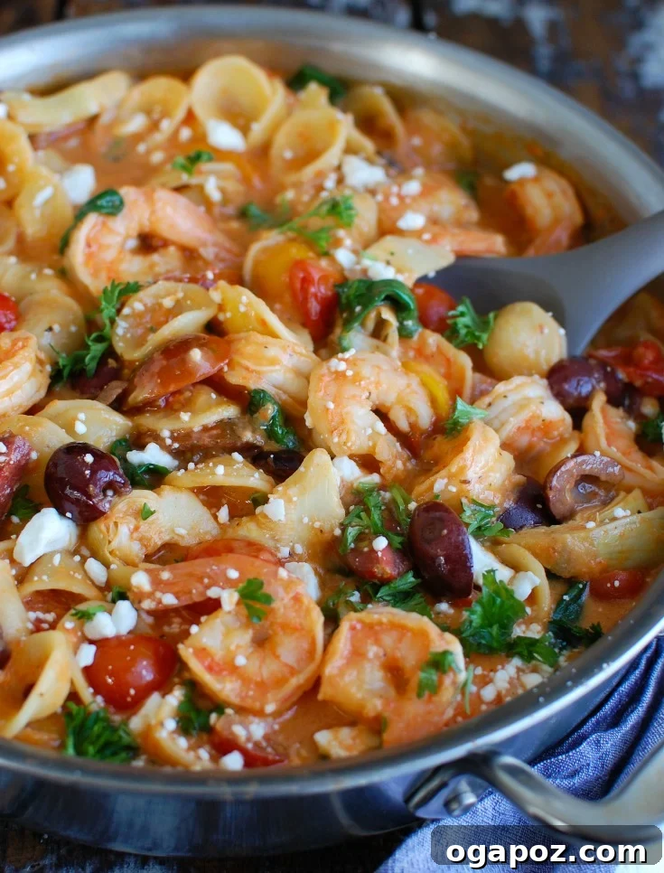 Close-up of fresh, colorful ingredients for One Pot Mediterranean Shrimp Pasta, including raw shrimp, sliced red onion, cherry tomatoes, Kalamata olives, and artichoke hearts, ready for cooking