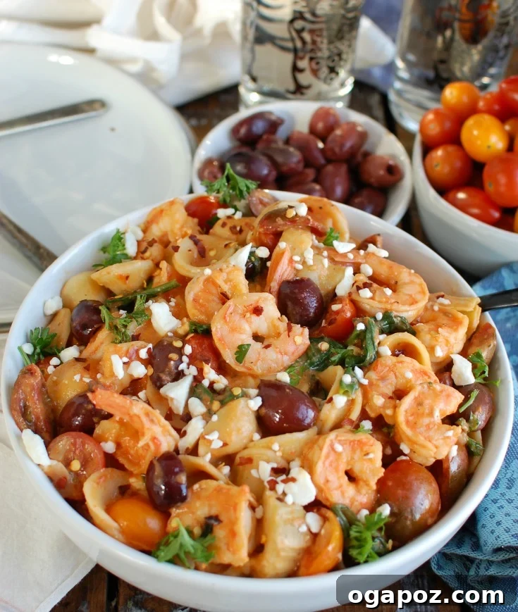 Overhead shot of One Pot Mediterranean Shrimp Pasta cooking and simmering in a large skillet, showing all the ingredients beautifully mixed together