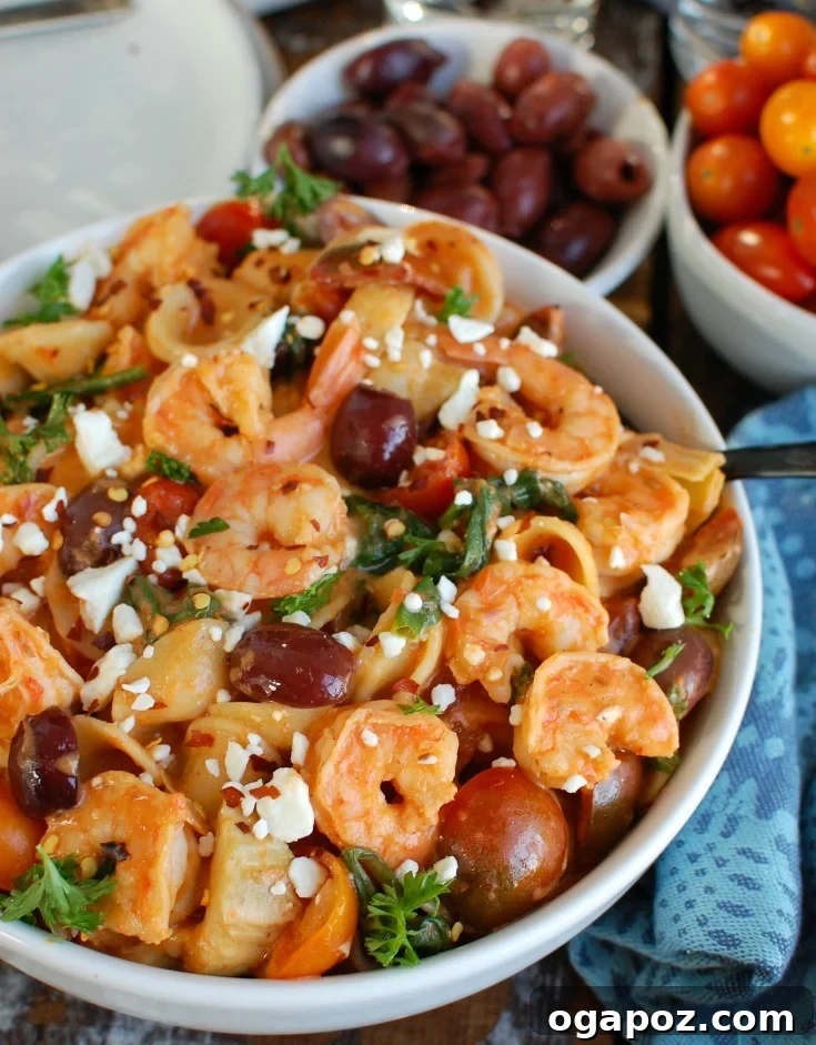 Serving of One Pot Mediterranean Shrimp Pasta in a white bowl with a fork, garnished with fresh herbs and a drizzle of olive oil, ready to eat