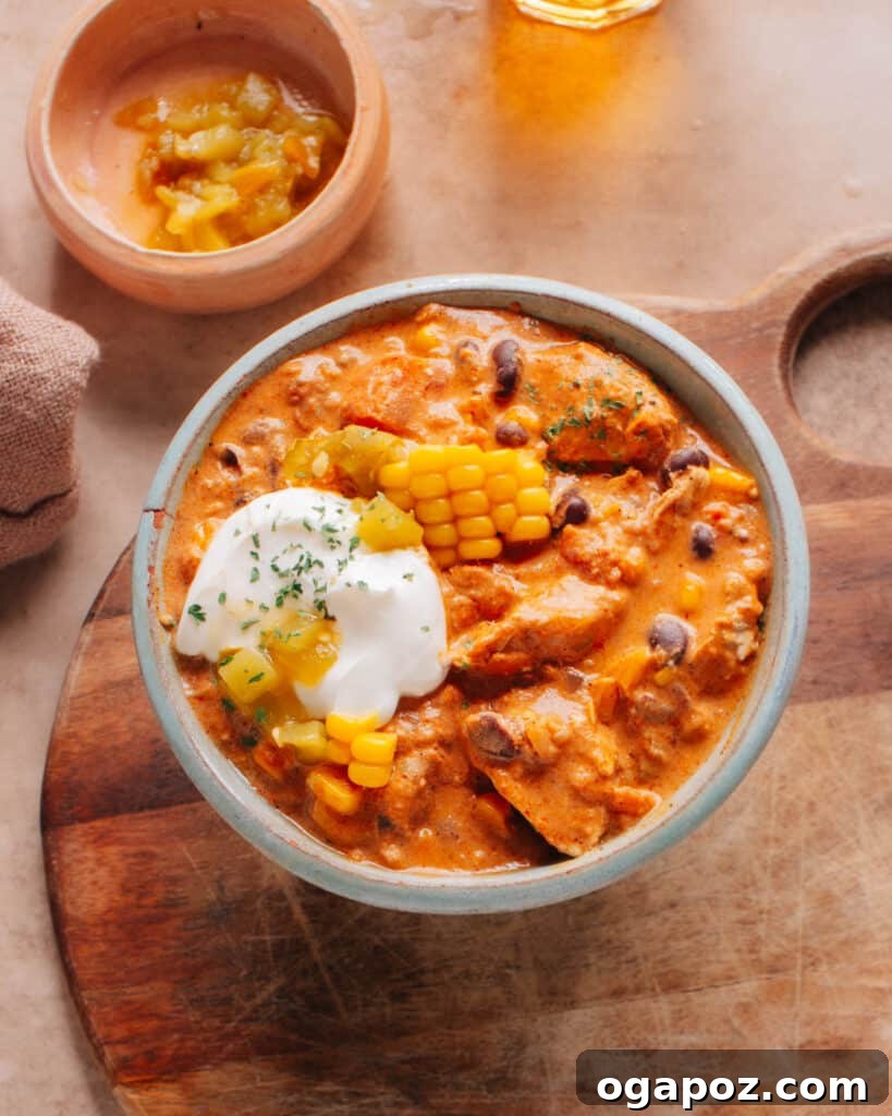 Velvet Chicken Chili 2 A hearty bowl of Cream Cheese Chicken Chili garnished with fresh corn kernels, sliced chilies, and a dollop of cream cheese, ready to be enjoyed.