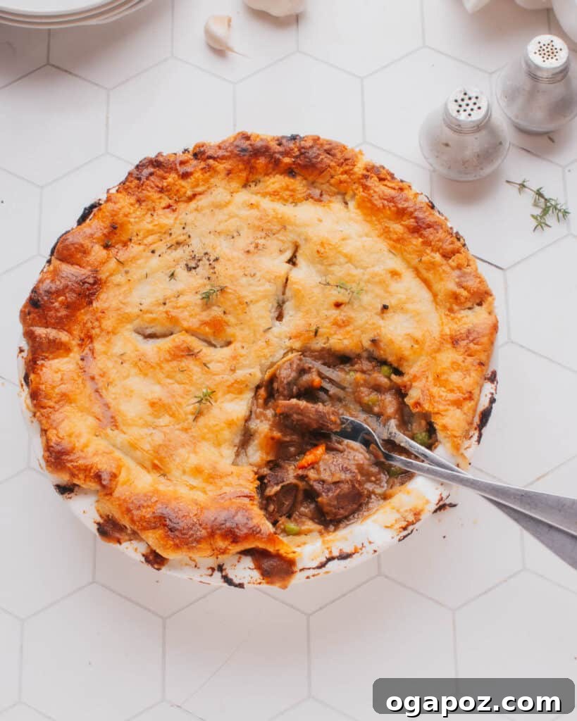 Rustic Beef Pot Pie 2 A delicious Beef Pot Pie with a slice removed, revealing the tender beef and rich gravy inside. Two forks are ready for serving.