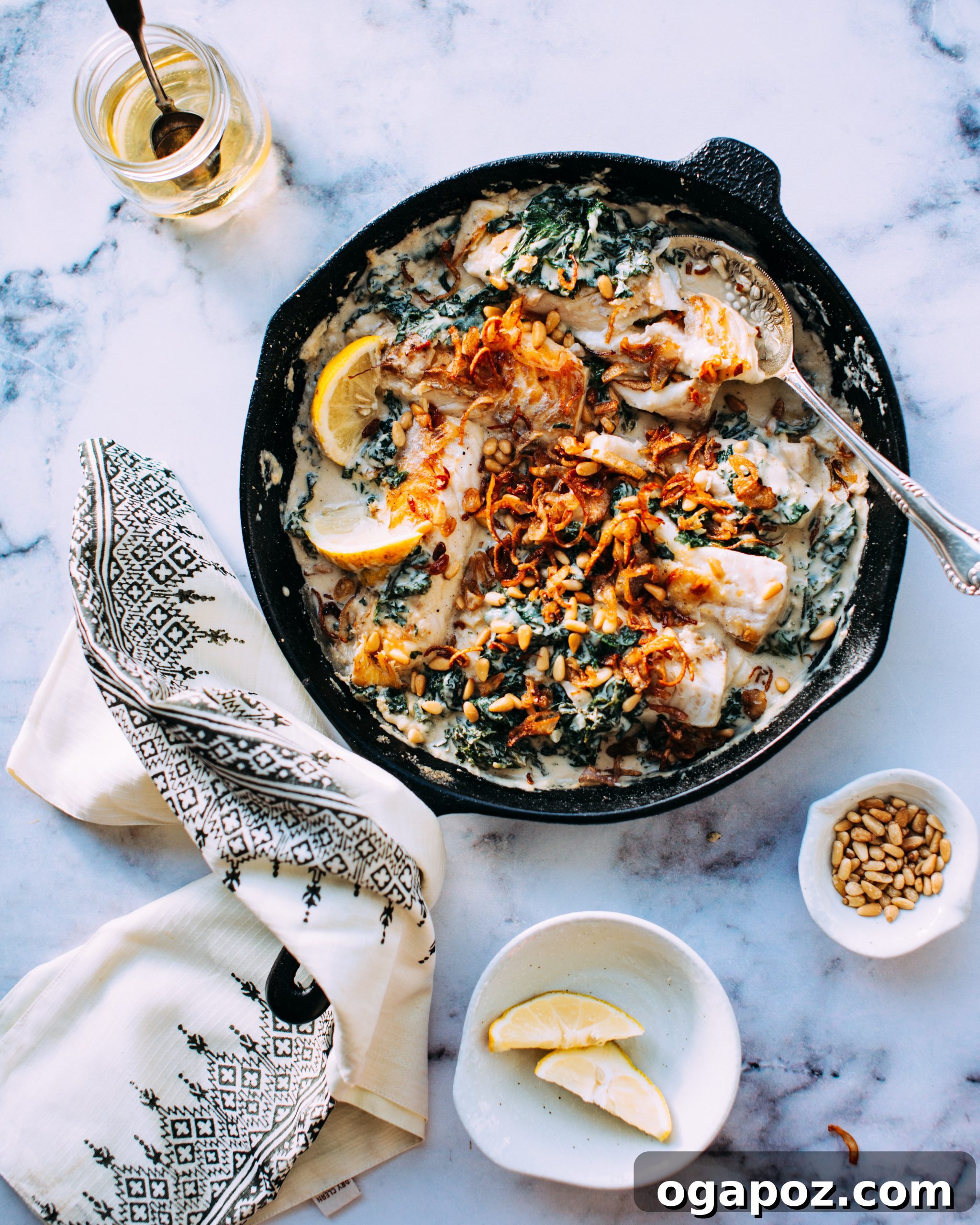 Creamy Tahini Fish and Kale with Golden Crispy Shallots 3 Close-up of haddock fish gently cooking in a large skillet, surrounded by creamy tahini sauce and vibrant kale.