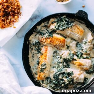 A vibrant close-up of the finished Fish and Kale in Tahini Sauce, garnished with crispy shallots in a skillet.