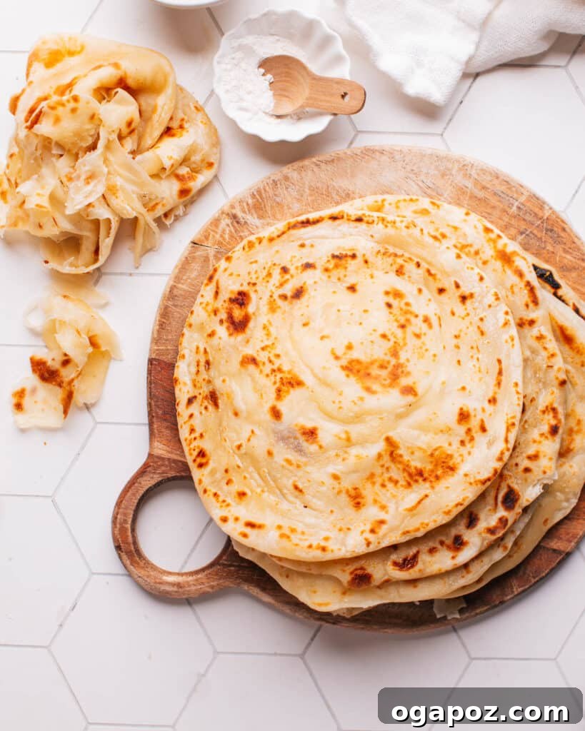 Golden Flaky Paratha Bread 2 Paratha on a board with some showing their flaky layers
