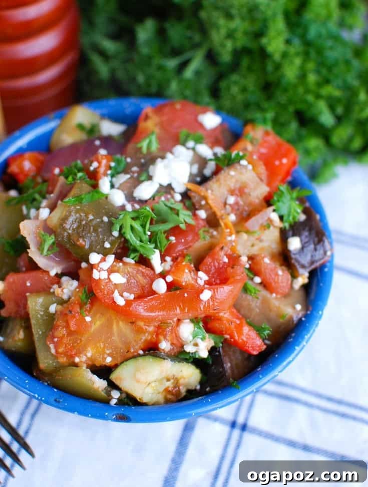 A vibrant platter of Greek Roasted Vegetables, known as Briami, featuring tender zucchini, eggplant, potatoes, and bell peppers in a rich tomato sauce, garnished with fresh parsley and crumbled feta cheese.