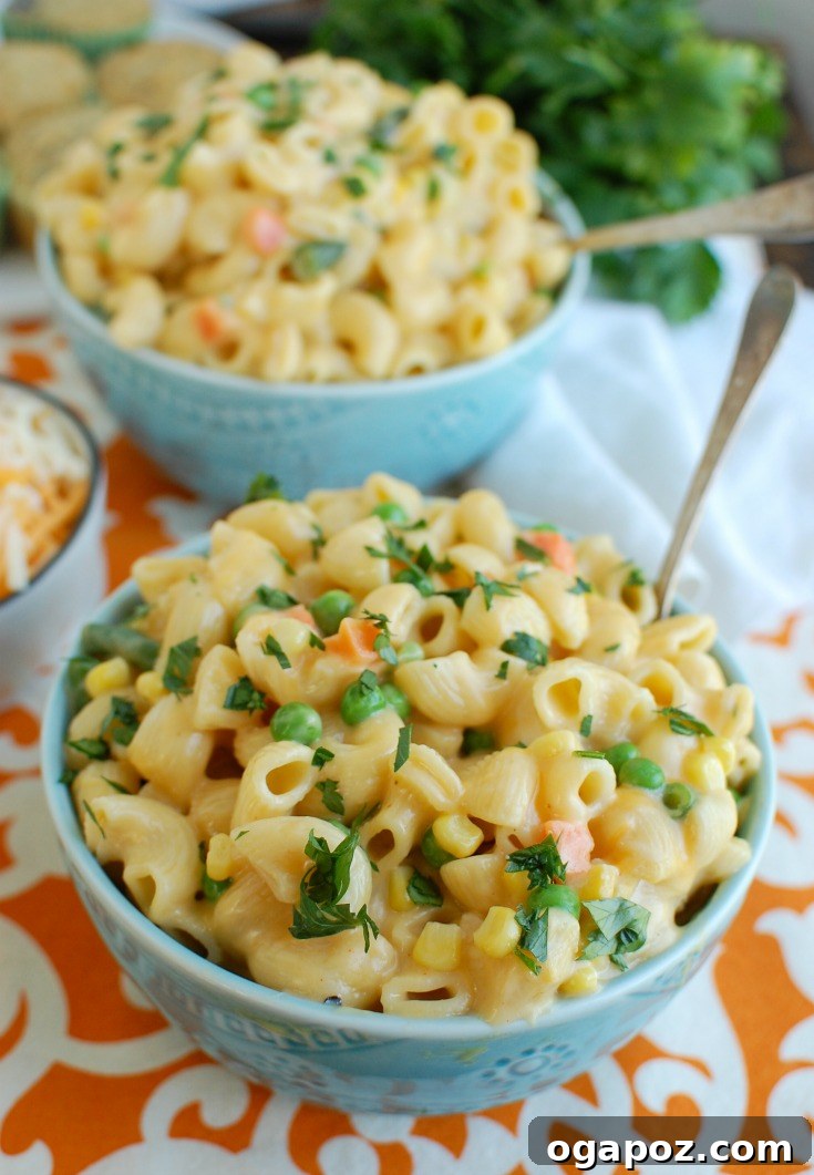 A vibrant blue bowl filled with creamy Instant Pot Vegetable Mac and Cheese, ready to be enjoyed with a spoon.