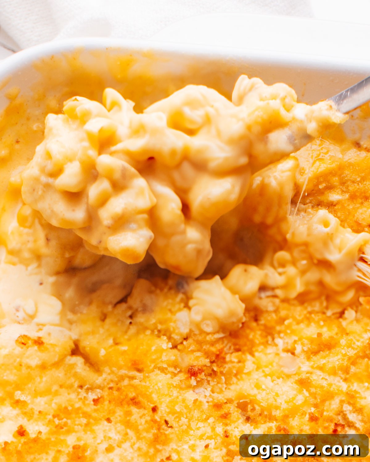 Classic Velvety Baked Macaroni and Cheese 16 A large serving of baked macaroni and cheese in a baking dish, with a serving spoon, ready to be dished out.