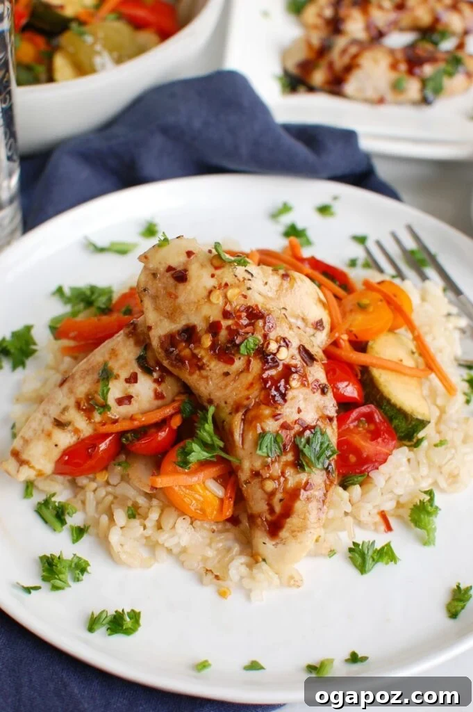 Sticky Balsamic Chicken & Roasted Veggies 2 A serving of Sheet Pan Honey Balsamic Chicken Tenders and Vegetables on a white plate, showcasing golden-brown chicken and colorful roasted vegetables.