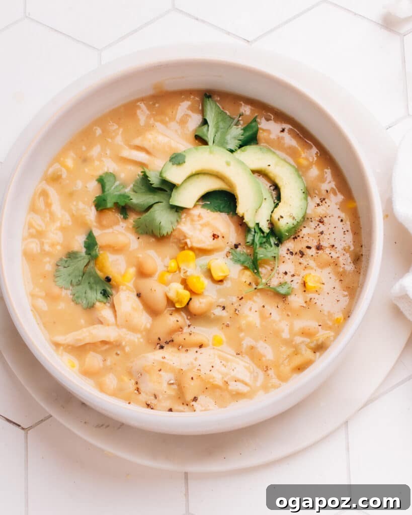 Wholesome White Chicken Chili 8 A beautifully presented bowl of creamy white chicken chili, garnished with avocado slices, fresh cilantro, and a lime wedge, ready to be enjoyed.