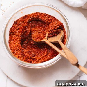 Homemade chili seasoning in a glass container with spoons.