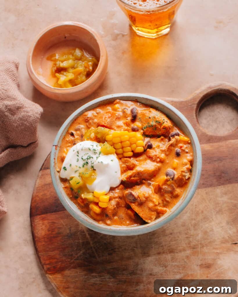 Secret Chili Seasoning Recipe 3 A comforting bowl of Cream Cheese Chicken Chili, generously topped with corn kernels, fresh chilies, and a dollop of cream cheese, ready to be enjoyed.