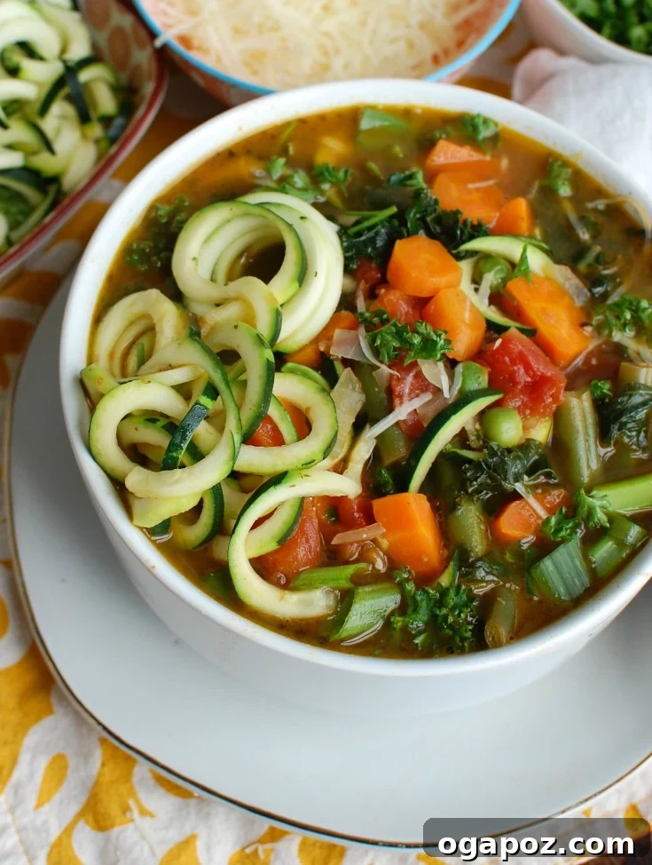Vibrant Spring Minestrone 2 A vibrant bowl of Spring Vegetable Minestrone soup, packed with fresh vegetables, zucchini noodles, and a swirl of pesto, presented in a side view against a rustic background. Perfect for a healthy vegan dinner or lunch.