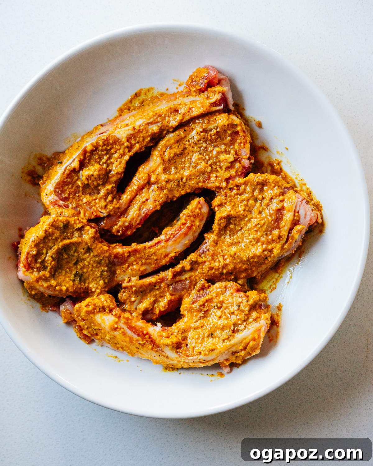 Maharaja's Lamb Chops 4 Lamb chops marinating in a vibrant Indian spice blend in a mixing bowl.