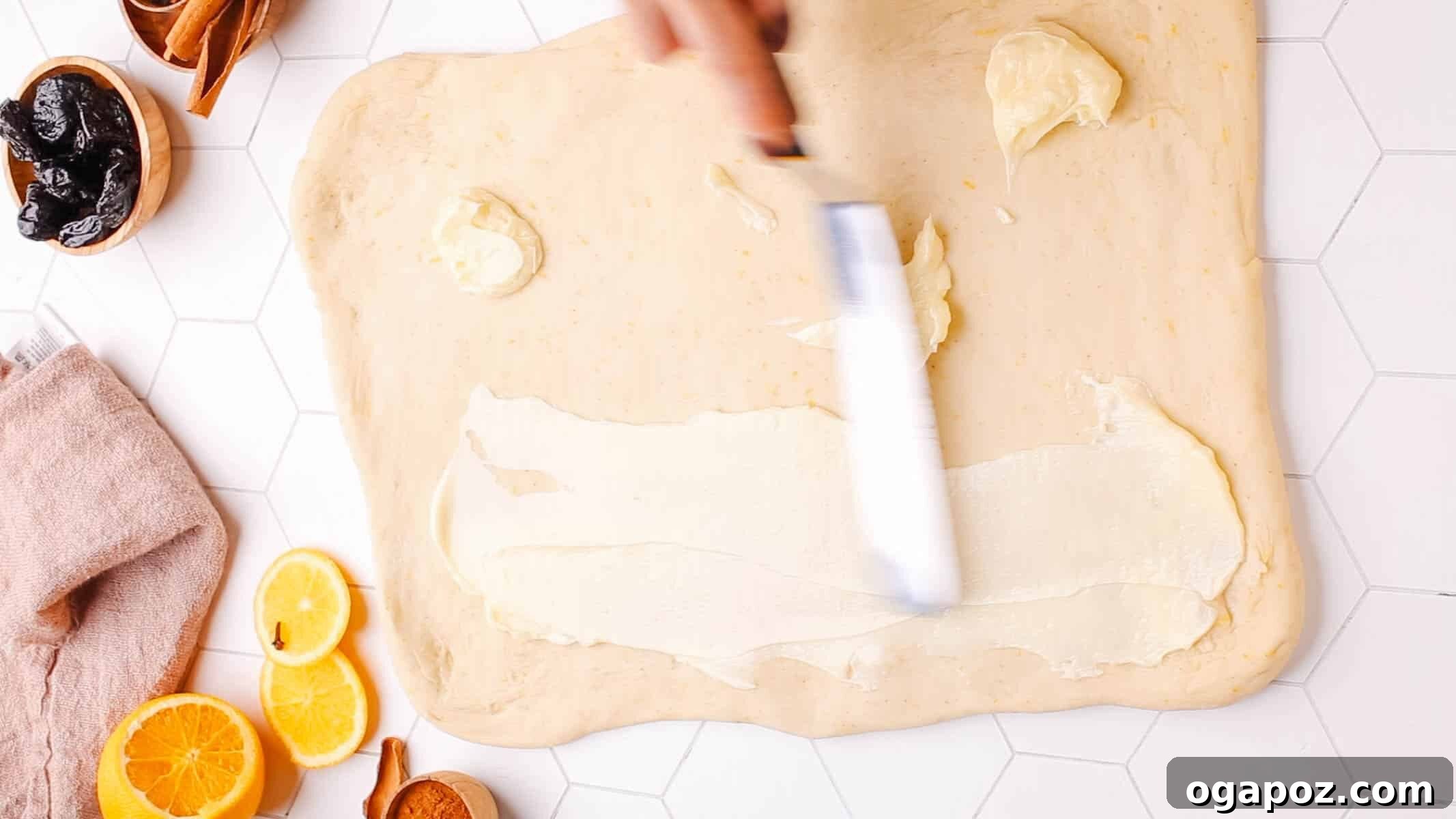 Sweet Cinnamon Swirls with Raisins 6 Softened butter being spread evenly across the surface of rolled-out cinnamon roll dough.